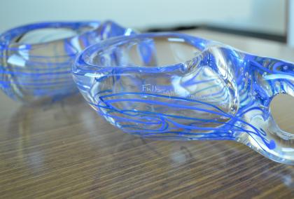 Two blue and white glass Kuksas on a table with "Fulbright Finland 70" carving on them
