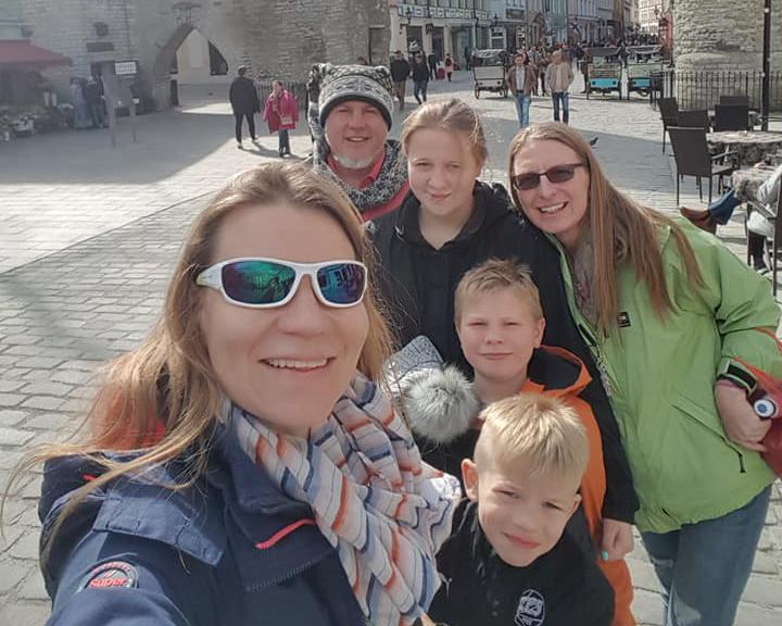 Bickford family with their friend taking a selfie, smiling to the camera. They are on a town square and the weather is sunny.