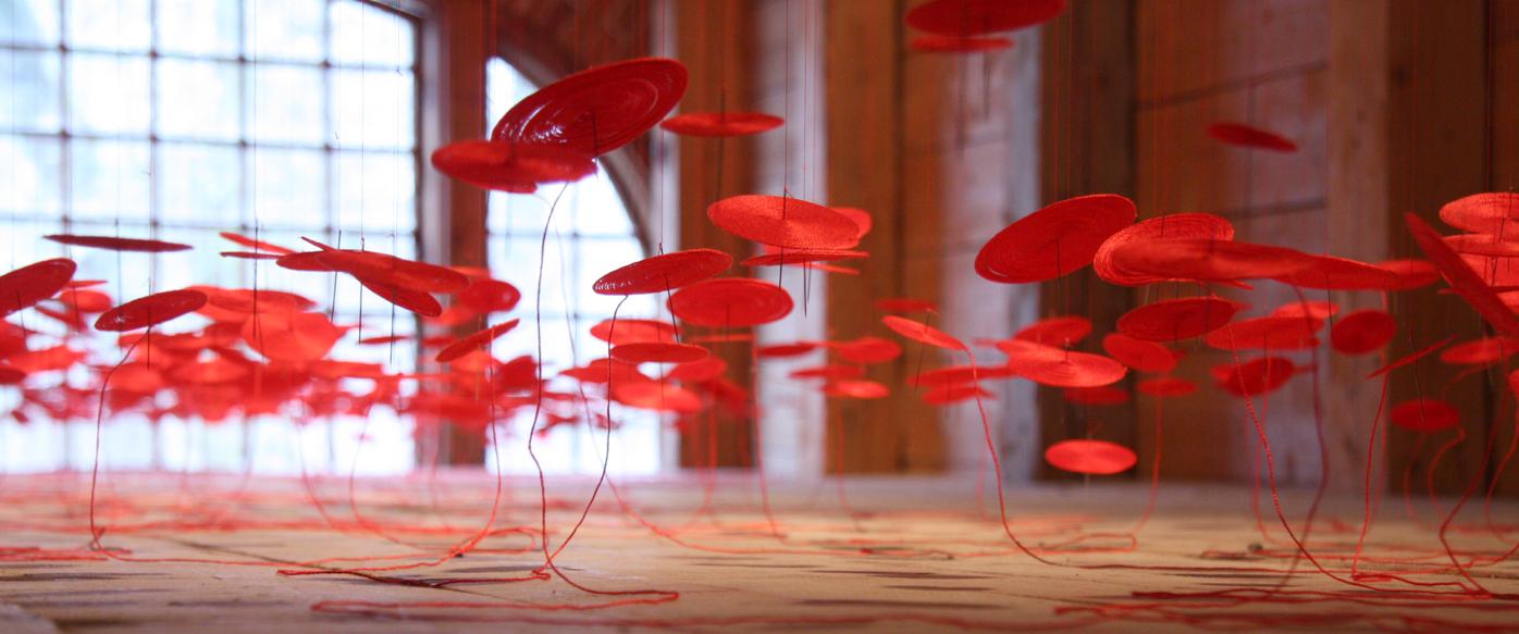 Lure, site-responsive installation at Fiskars. The installation is red, made with thread, needles