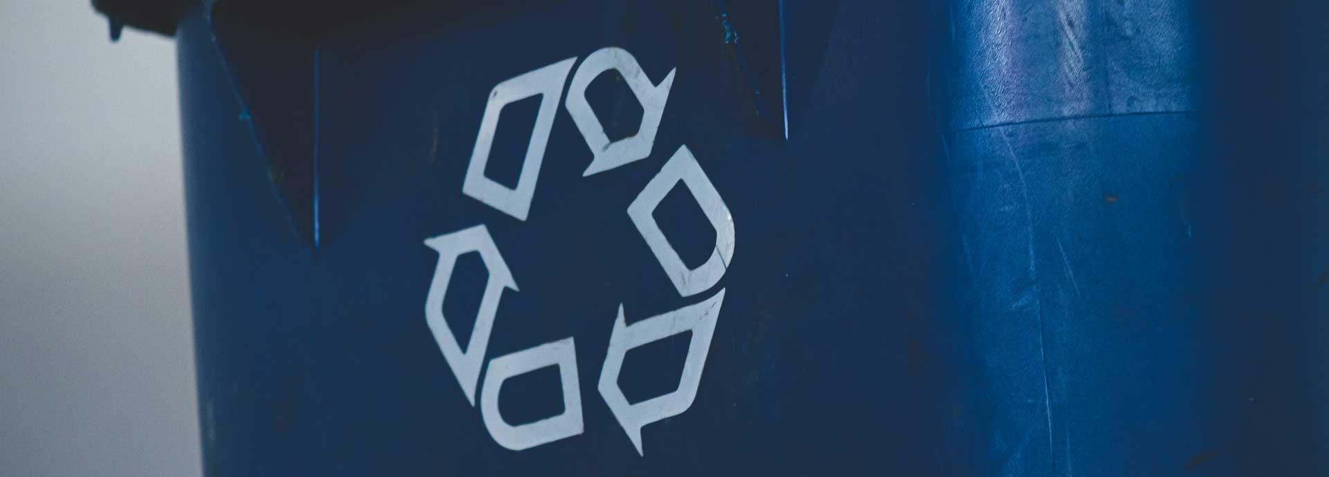 A recycle symbol on a blue trash bin