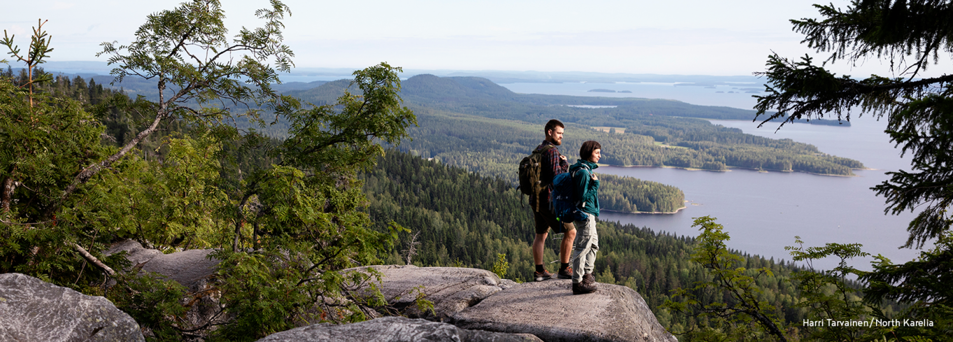 Two people standing on a hill at Koli National Park looking at the lake view