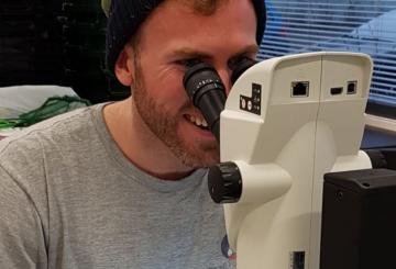 A man looking at a sample through a microscope