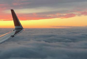 Wing of an airplane and sunset on the background
