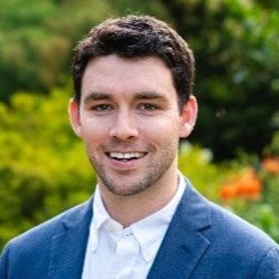 Photo of a man in a blue suit jacket and white shirt