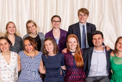 2018-2019 U.S. Fulbright Fellows sitting in two rows and hugging each other, smiling at the camera at the Helsinki City Hall after 2019 Fulbright Award Ceremony