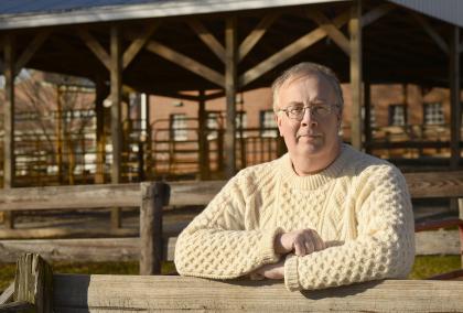 Photo of Professor of Toxicology David Dorman at a farm-like surroundings. He is wearing a white cardigan and looking directly to the camera.