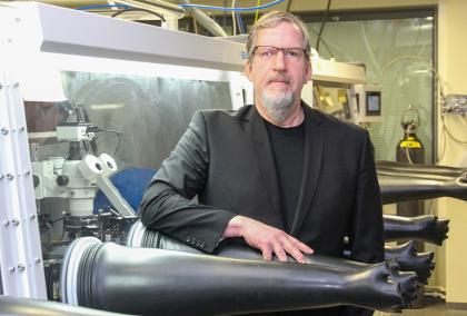 Fulbright-Nokia Distinguished Chair in Information and Communications Technologies in a laboratory, standing among long and black glove-like items.