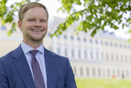 Photo of Jukka Välimaa taken in front of the Ministry for Foreign Affairs Merikasarmi building on a sunny summer day.