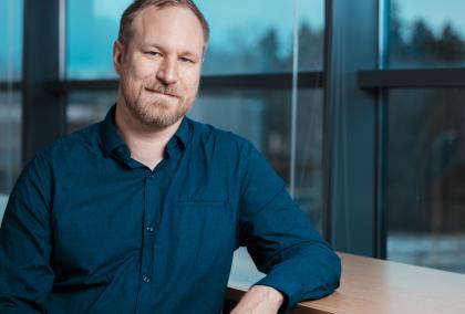 Jussi Paananen leaning lightly on a handrail in front of a window