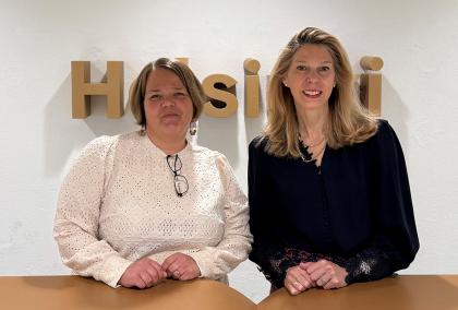 Kristen Edgreen Kaufman and Laura Uuttu-Deschryvere at Helsinki City Hall in front of HELSINKI sign