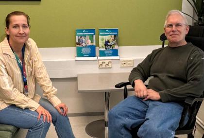 Sini Bask and Chris Zirkle smiling at the camera. Sini is sitting on the left on a couch and Chris on the right on a rocking chair.