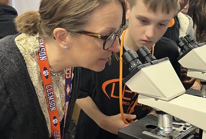 Tarja Kariola and a student looking through a microscope in a classroom setting