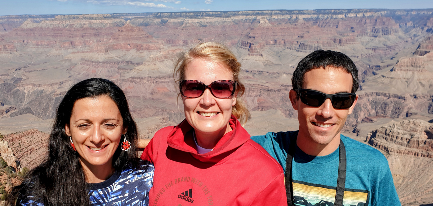 Three people standing in front of a canyon. They all are wearing sunglasses.