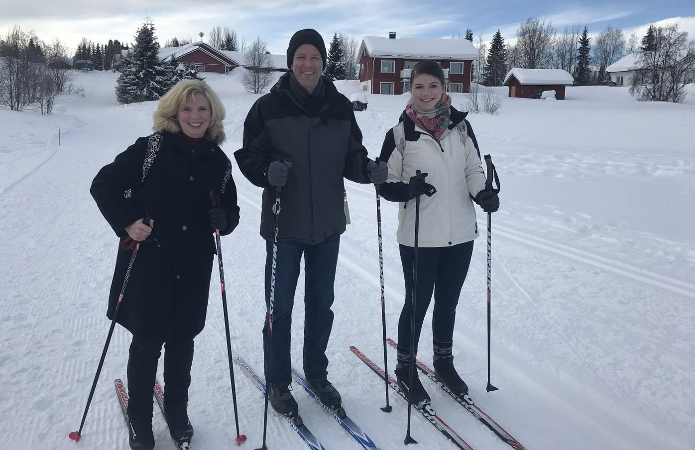The Buchanan family on cross-country skiis at Ylläs, there is snow around them, and they are all smiling at the camera.
