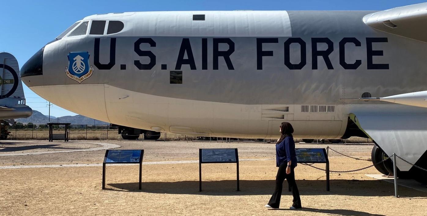 Salima Alaoui walking in front of a U.S. Air Force plane at the National Museum of Nuclear Science and History.