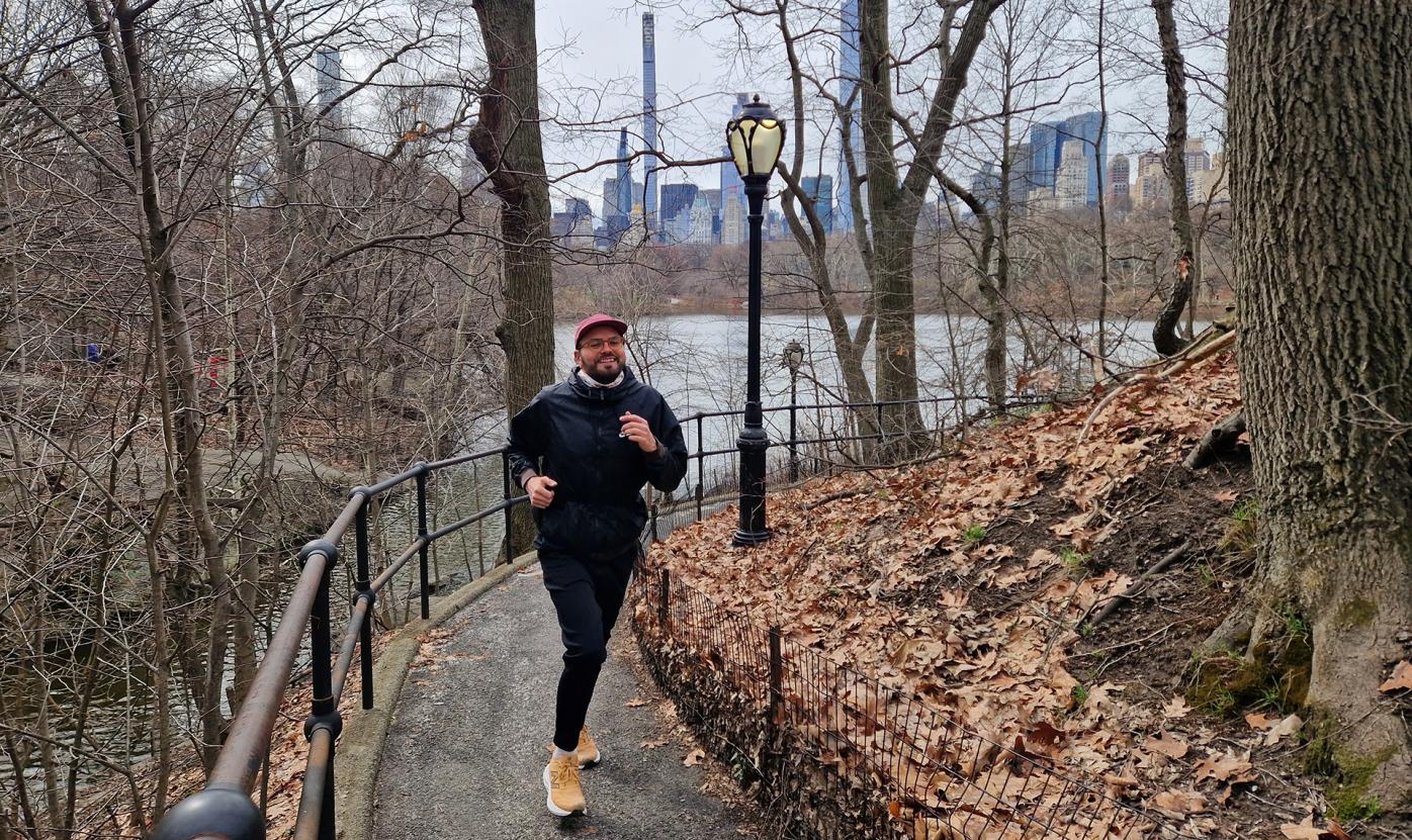 Jaakko Dickman running in a park in New York City, with the city skyline in the background.