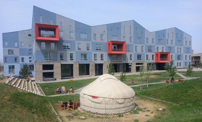 AUCA campus photo showing modern building in the background and a large yurt on the front.