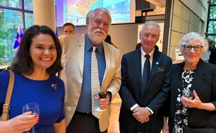 Four Fulbright Finland alumni smiling at the camera during a networking reception