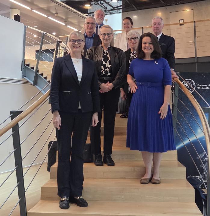 8 people standing on the stairs at the Embassy of Finland in D.C., smiling at the camera