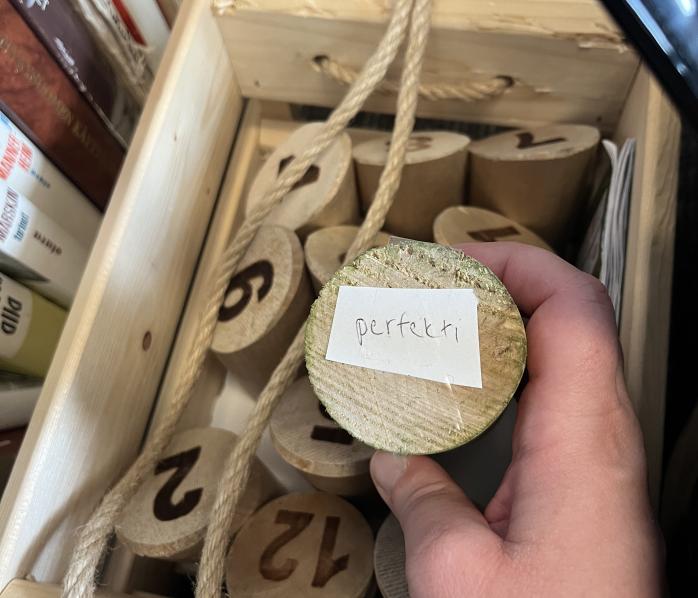 Mölkky pin with a word "perfekti" on it, a part of an escape room game requiring Finnish language skills