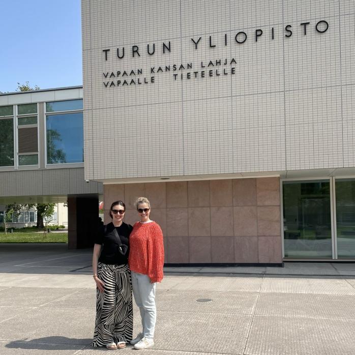 Two persons standing in front of the University of Turku main building