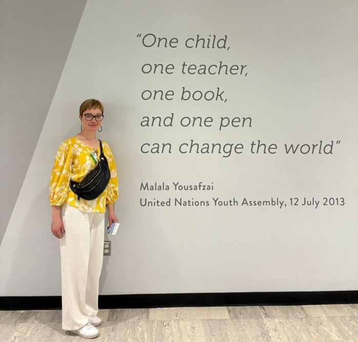 Person in front of a wall showing a quote by Malala Yousafzai