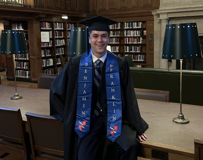 Patrik Haverinen in a graduation gown in a library