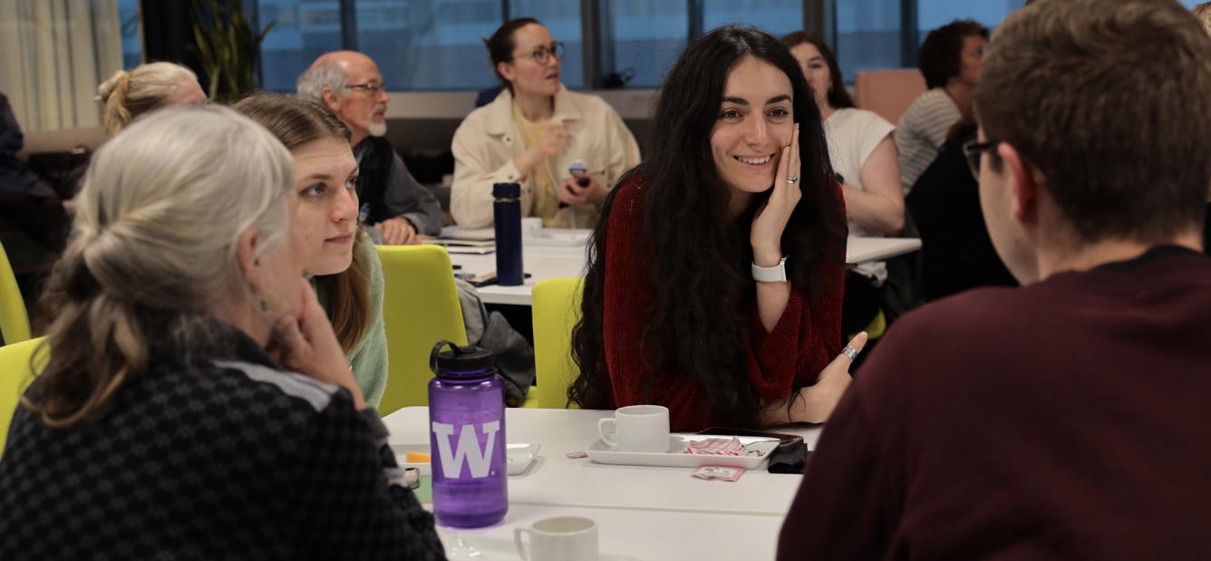 A group of people sitting at tables, two people opposite of each other are having a conversation during a workshop