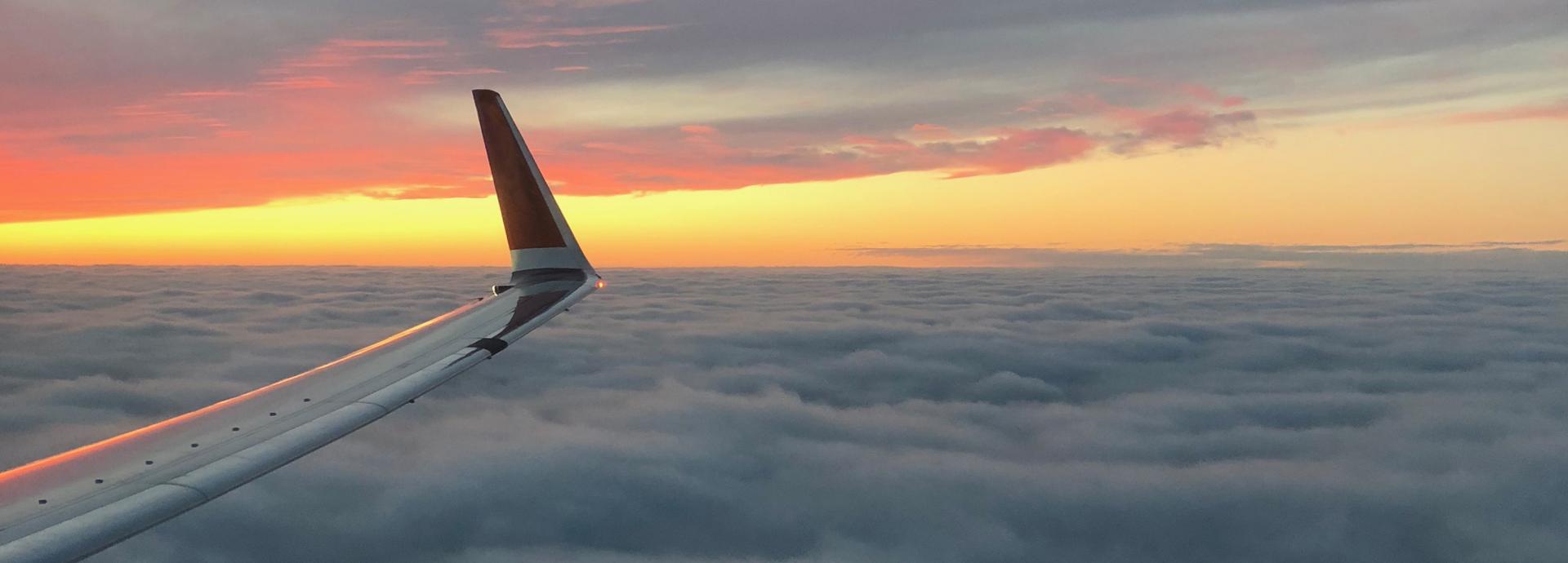 Wing of an airplane and sunset on the background