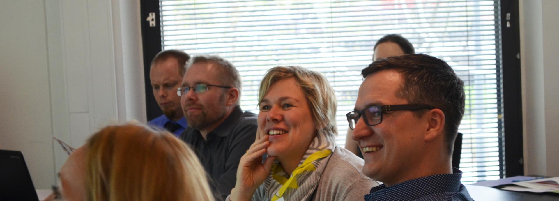 Three men and one woman looking at something during orientation and laughing.