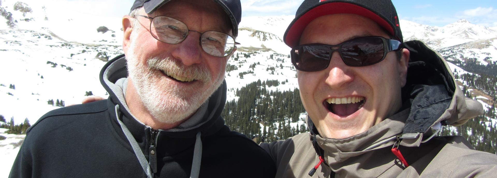 Fulbrighters Micheal H. Epstein and Erkko Sointu taking selfie on a top of a mountain, Loveland Pass in Colorado. It's sunny day, Erkko is wearing sun glasses and both of them are smiling widely to the camera.