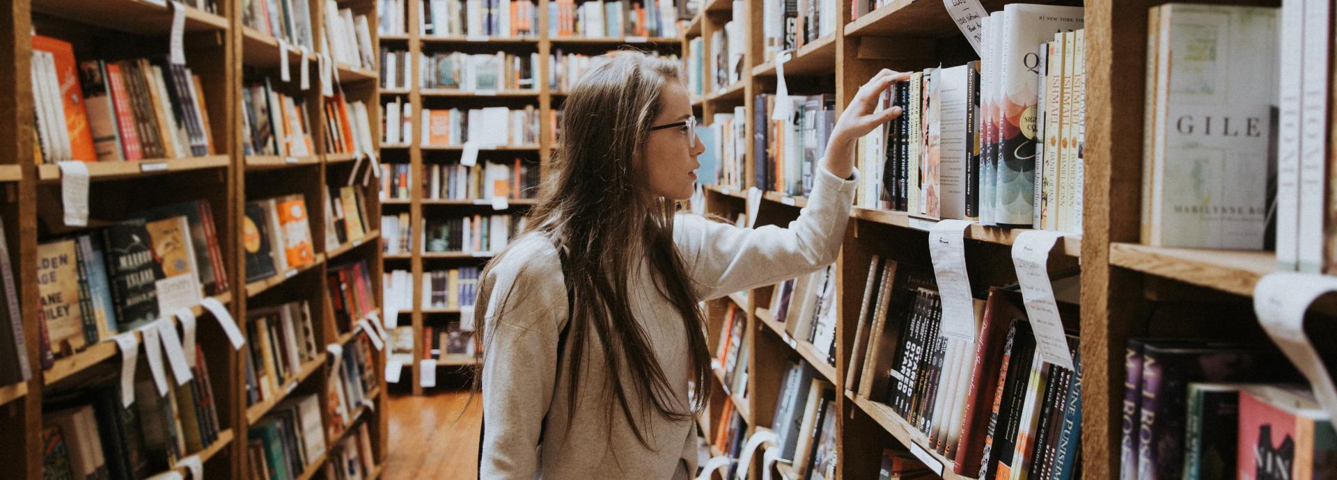 A girl searching books in a library.