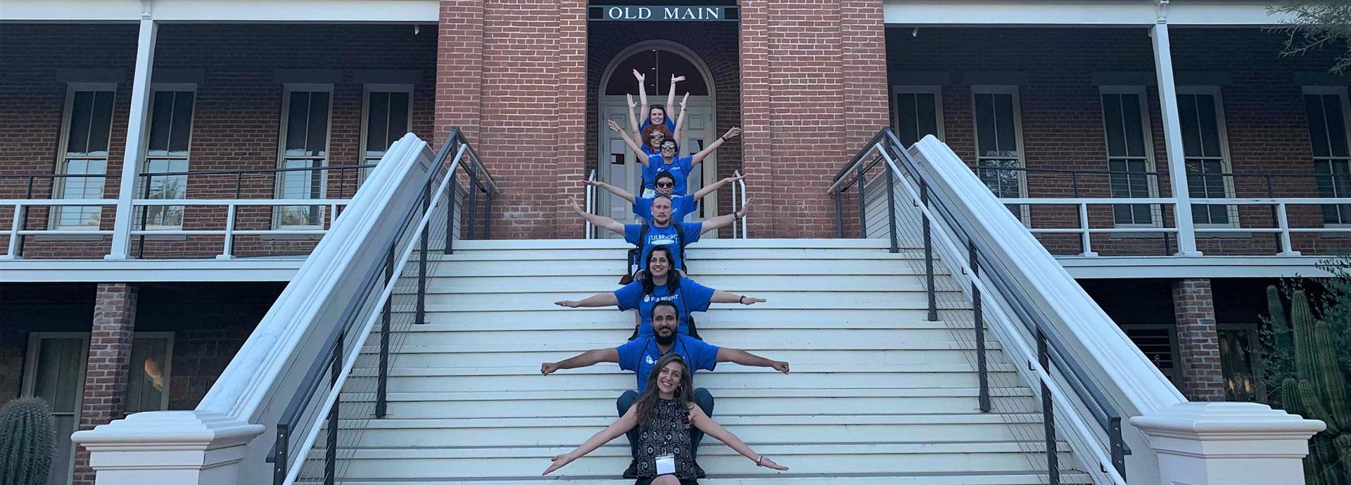 Group of students sitting in a line on university campus' building stairs