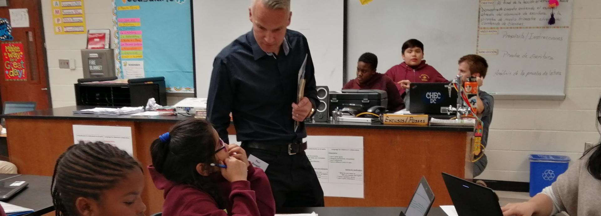 Teacher observing students' work in a classroom