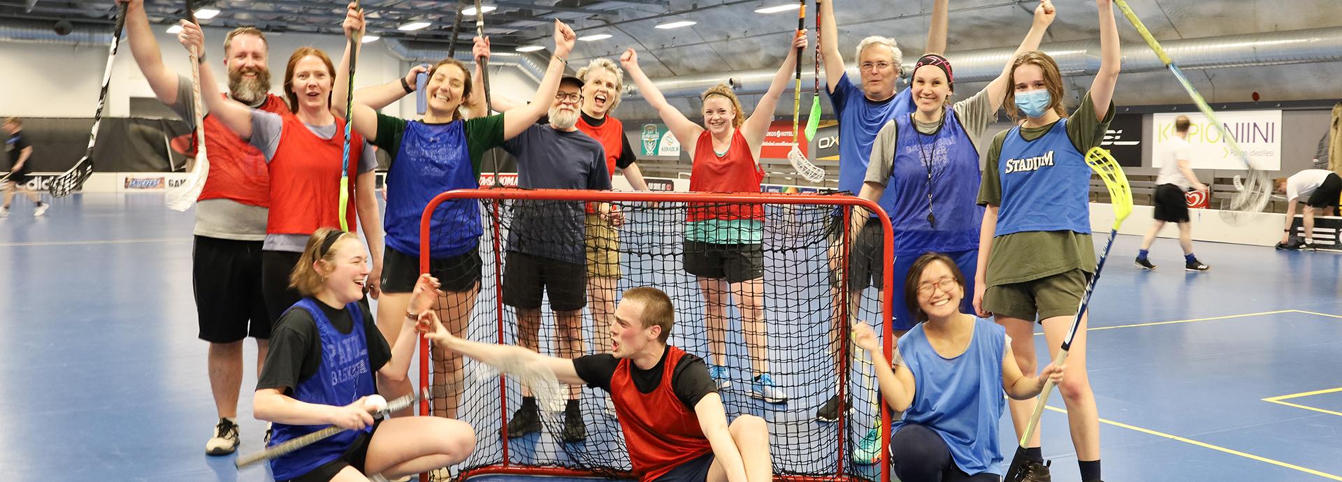 Fulbrighter at floorball court, waving their hands with the sticks up in the air. 