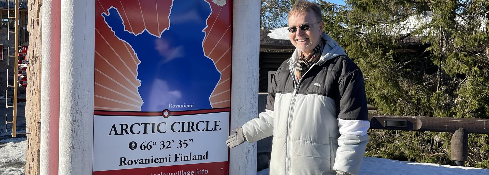 Fulbright Specialist John Donnellan next to the Artic Circle sign in Rovaniemi on a sunny winter day.