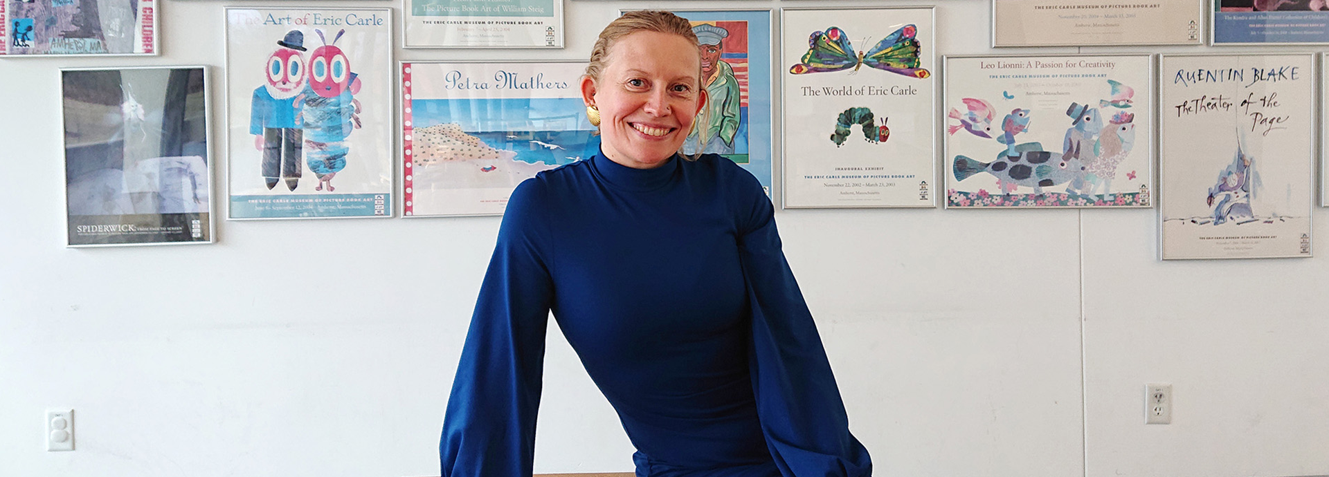 Pirita Tolvanen sitting by a desk with posters behind her on a wall