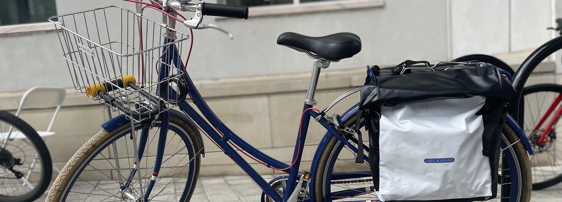 A dark blue bicycle that has a basket in the front and panniers in the back.