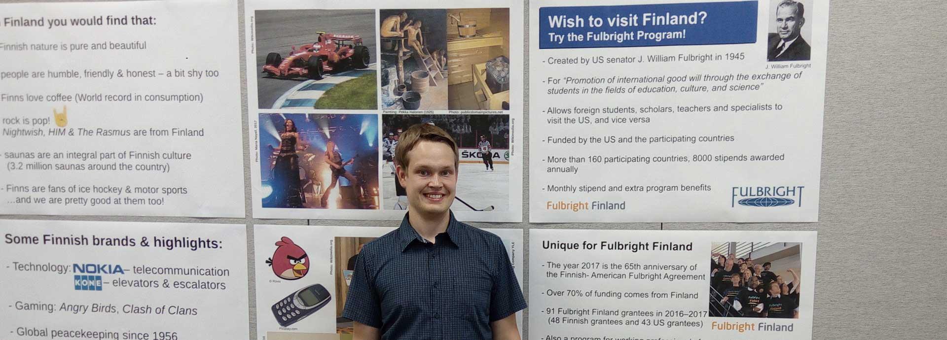 Fulbright Finland grantee Lauri Kivijärvi in front of posters about Finland and Fulbright Finland Foundation