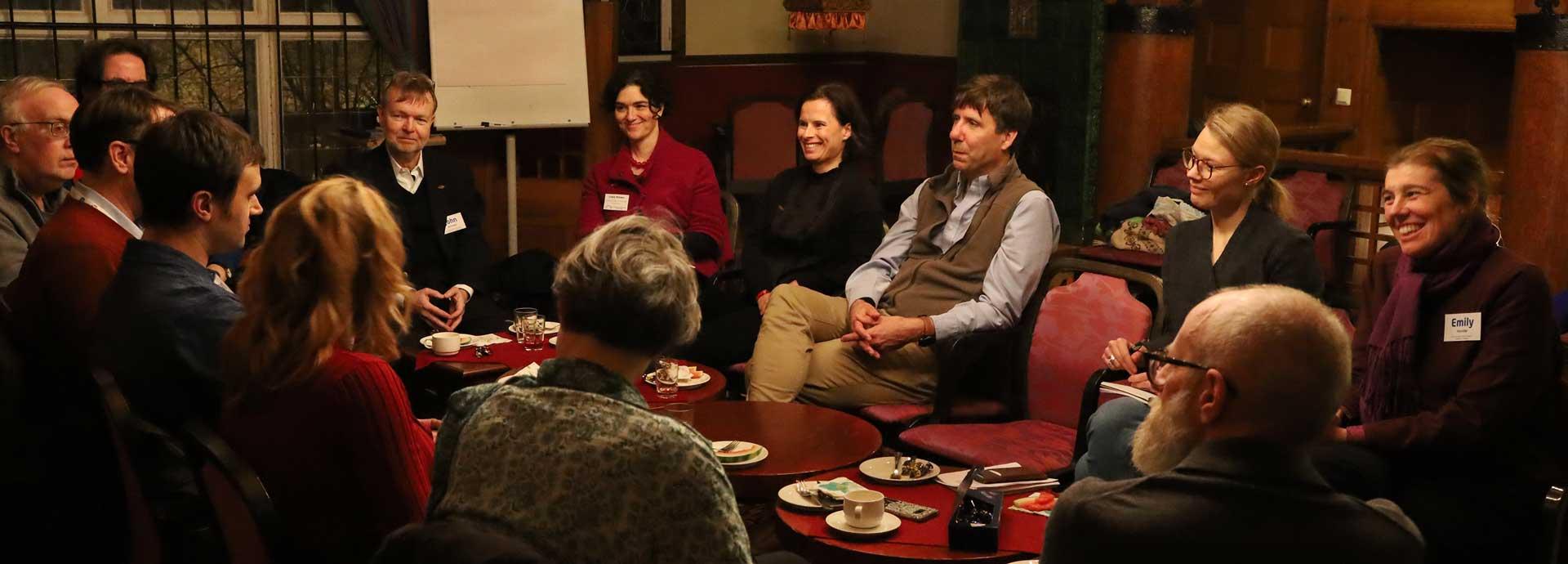 Group of alumni and grantees talking and laughing around a table