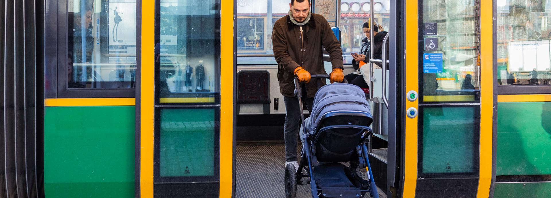 A man with a stroller exiting a tram