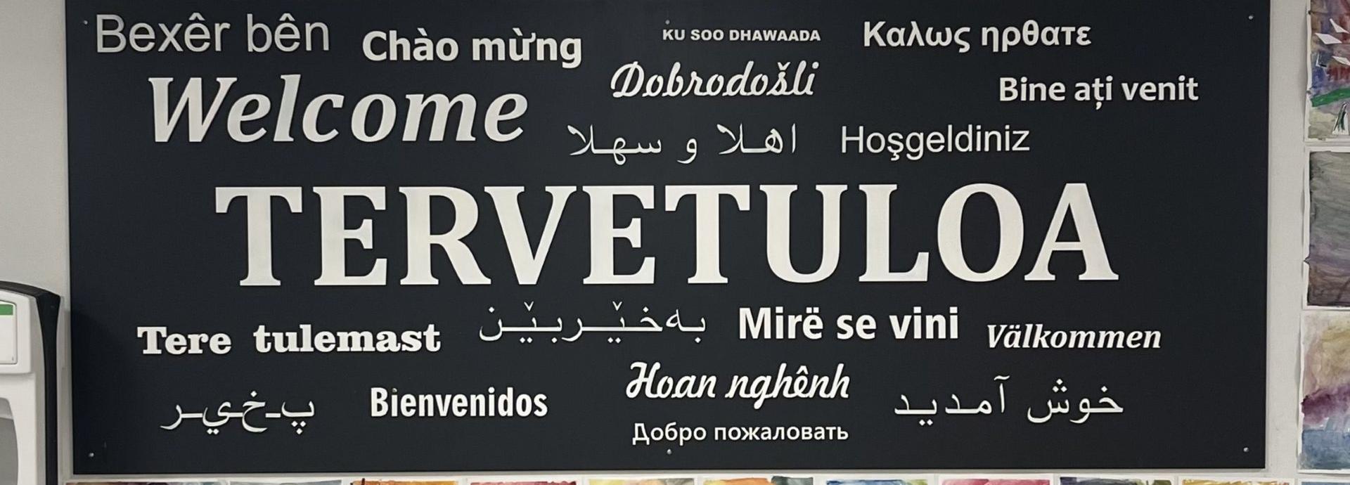 A sign of the word Welcome in different languages, with the biggest being the Finnish Tervetuloa