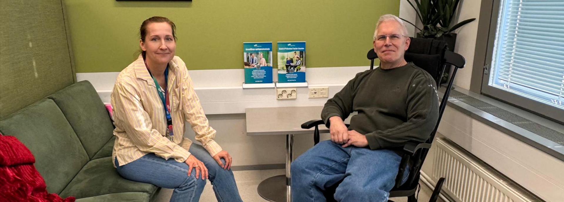 Sini Bask and Chris Zirkle smiling at the camera. Sini is sitting on the left on a couch and Chris on the right on a rocking chair.