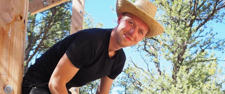 Architect student Pekko Sangi smiling at the camera in a construction site in sunny New Mexico