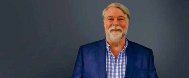 Bill Eaton smiling in front of a grey background