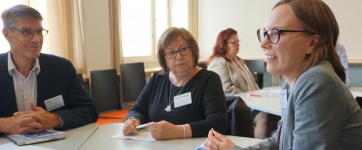 Three people discussing around a table in a classroom