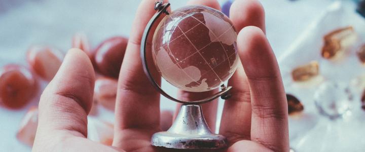 A person holding a globe made of glass in their hand.