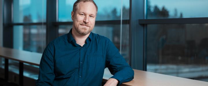 Jussi Paananen leaning lightly on a handrail in front of a window