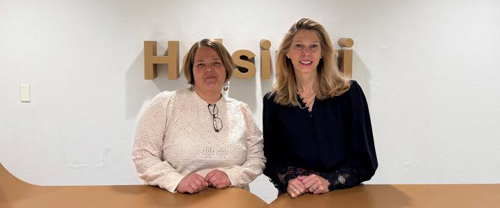 Kristen Edgreen Kaufman and Laura Uuttu-Deschryvere at Helsinki City Hall in front of HELSINKI sign