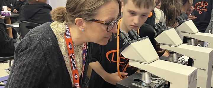 Tarja Kariola and a student looking through a microscope in a classroom setting